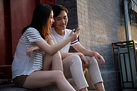 青年情侣坐在门口看手机图片