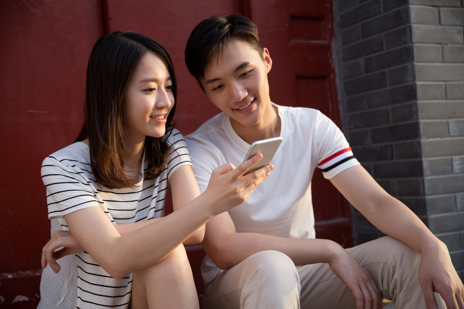 青年情侣坐在门口看手机 青年情侣坐在门口看手机