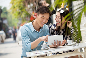 青年情侣坐在咖啡馆看平板电脑