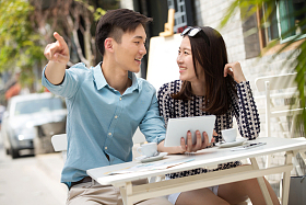 青年情侣坐在咖啡馆看平板电脑