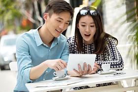 青年情侣坐在咖啡馆里看平板电脑