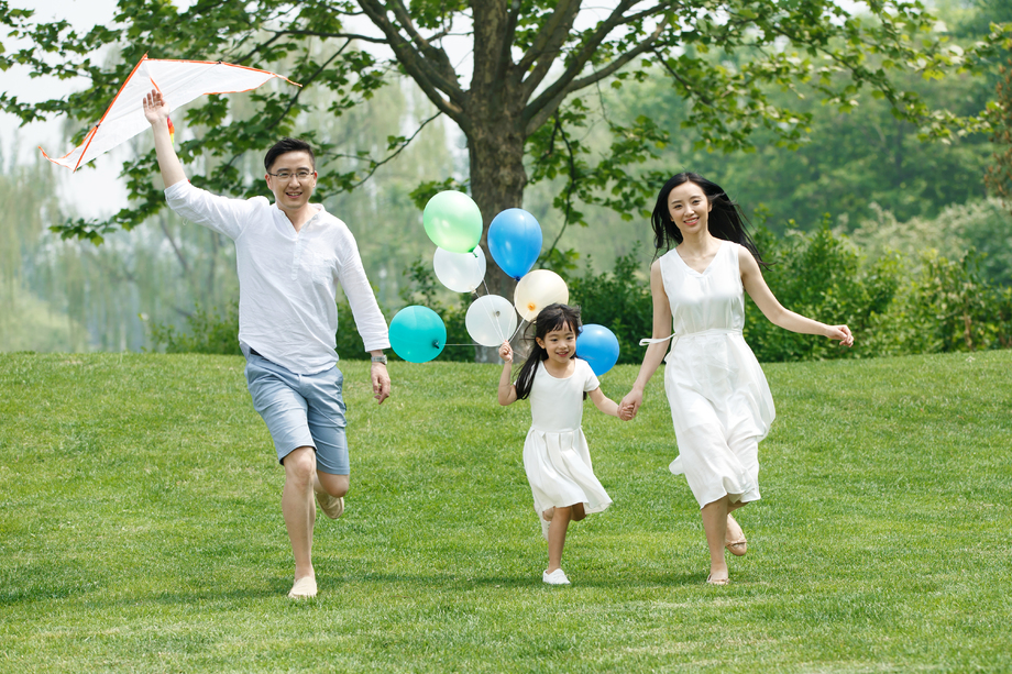一家三口在草地上放风筝照片