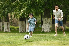 快乐父子在草地上踢足球照片