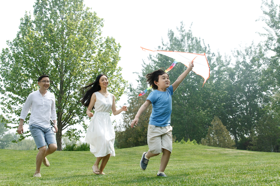 一家三口在草地上放风筝照片