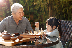 祖父和孙女在庭院里下棋图片