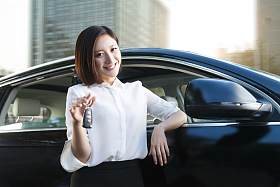 青年女人拿着车钥匙站在汽车旁边