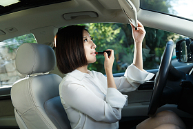 青年女人坐在车里化妆