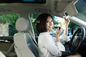 青年女人坐在车里化妆