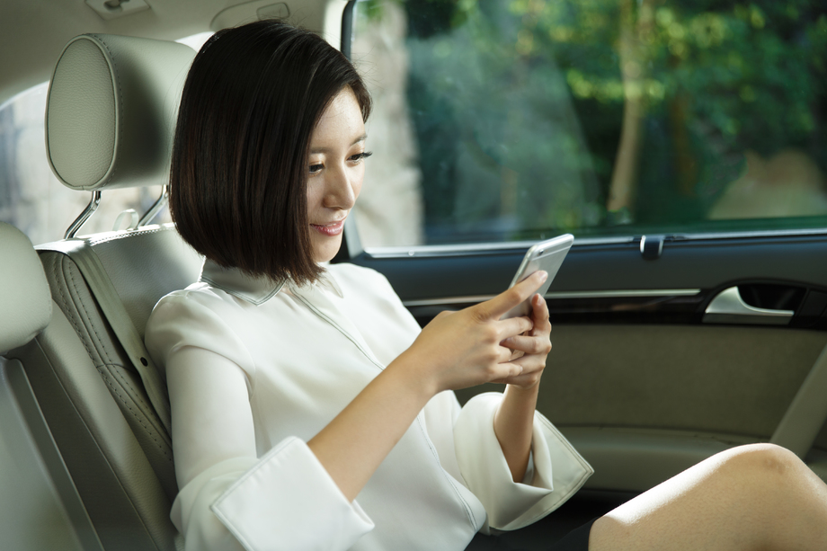 青年女人坐在汽车里看手机照片