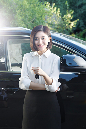 青年女人拿着车钥匙站在汽车旁边
