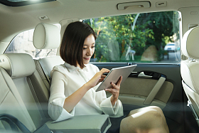 青年女人坐在汽车里看平板电脑