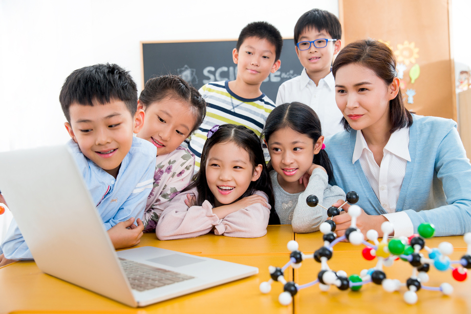 女教师和小学生在教室里使用电脑 女教师和小学生在教室里使用电脑