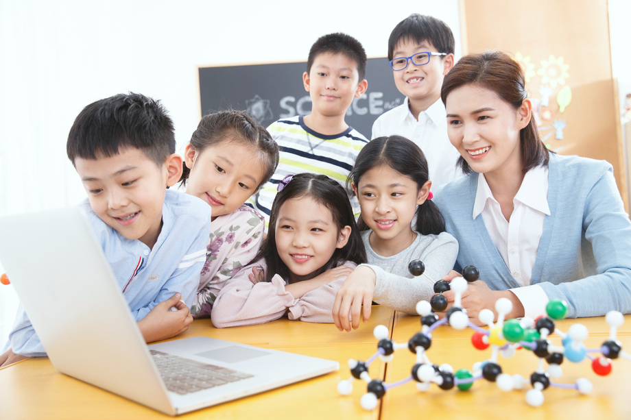 女教师和小学生在教室里使用电脑 女教师和小学生在教室里使用电脑