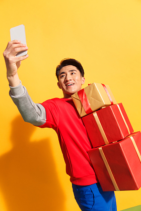 拿着礼品盒的青年男人看手机