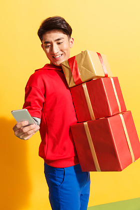 拿着礼品盒的青年男人看手机图片