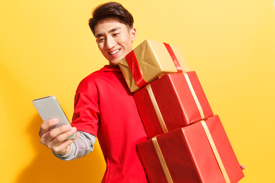 拿着礼品盒的青年男人看手机照片 拿着礼品盒的青年男人看手机照片