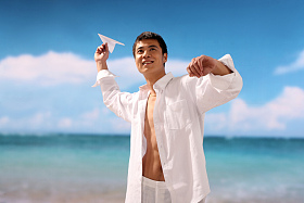 东方男人在海滩扔纸飞机