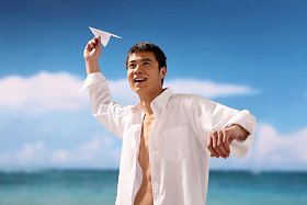 东方男人在海滩扔纸飞机图片