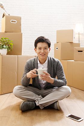 青年男人坐在地板上喝水图片