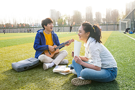 青年大学生在校园里弹奏吉他