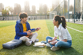 青年大学生在校园里弹奏吉他照片