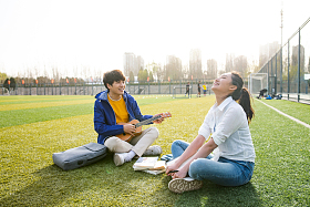 青年大学生在校园里弹奏吉他图片