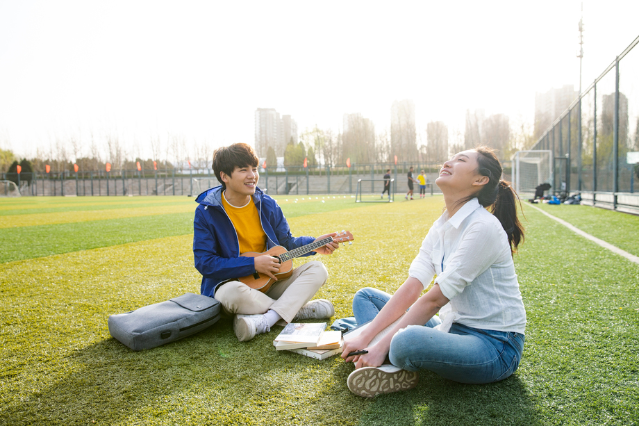 青年大学生在校园里弹奏吉他图片
