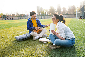 青年大学生在校园里弹奏吉他图片