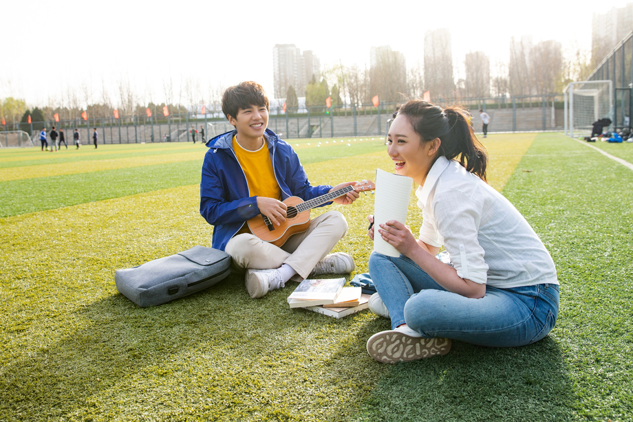 青年大学生在校园里弹奏吉他图片