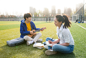 青年大学生在校园里弹奏吉他图片