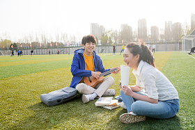 青年大学生在校园里弹奏吉他