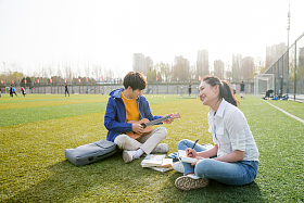 青年大学生在校园里弹奏吉他图片