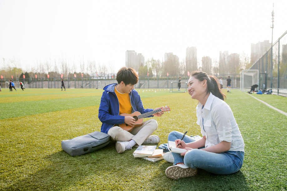 青年大学生在校园里弹奏吉他图片