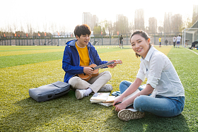 青年大学生在校园里弹奏吉他