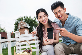 青年伴侣坐在户外展示手机图片