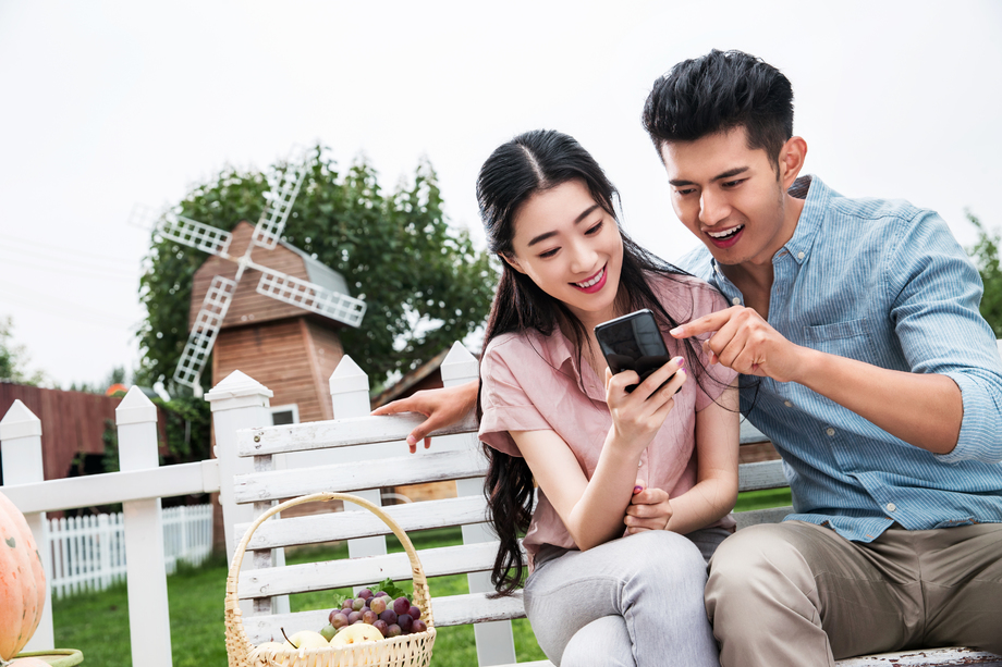 青年伴侣坐在户外看手机图片 青年伴侣坐在户外看手机图片