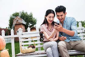 青年伴侣坐在户外看手机图片