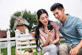 青年伴侣坐在户外看手机图片