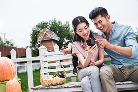 青年伴侣坐在户外看手机