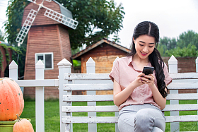 青年女人坐在户外看手机图片