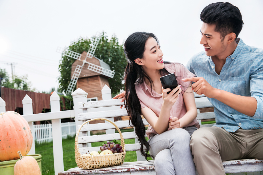 青年伴侣坐在户外看手机图片