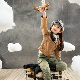 坐在行李箱上快乐的女孩拿着飞机模型