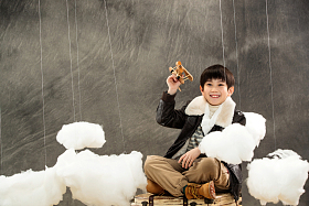 拿着飞机模型坐在行李箱上的男孩