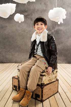 小男孩坐在复古行李箱上照片