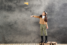 站在行李箱上扔纸飞机的小女孩