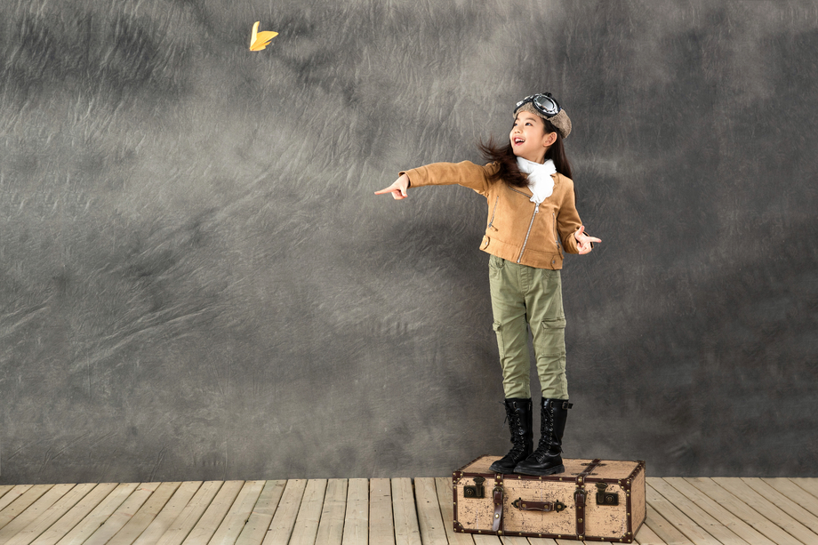 站在行李箱上扔纸飞机的小女孩