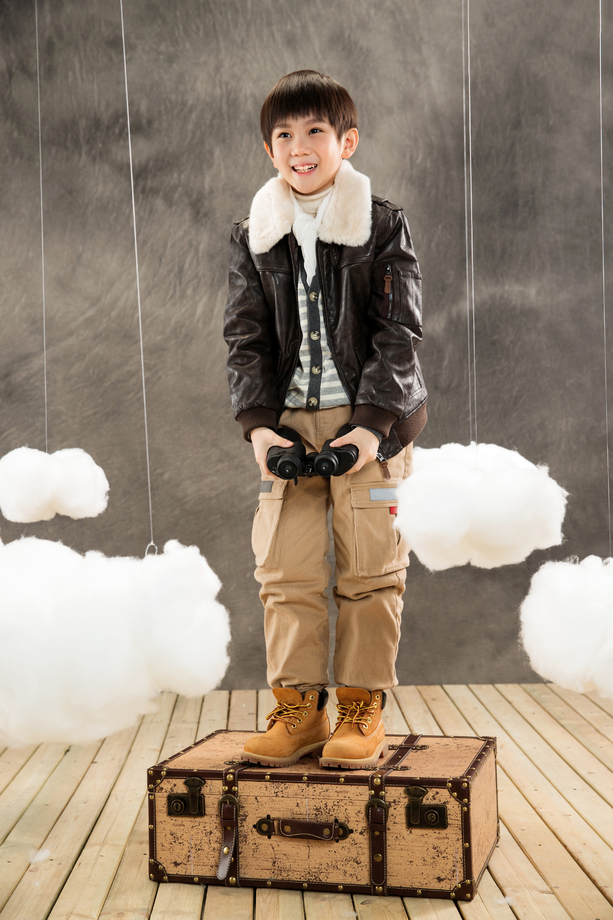 快乐男孩拿着望远镜站在行李箱上 快乐男孩拿着望远镜站在行李箱上