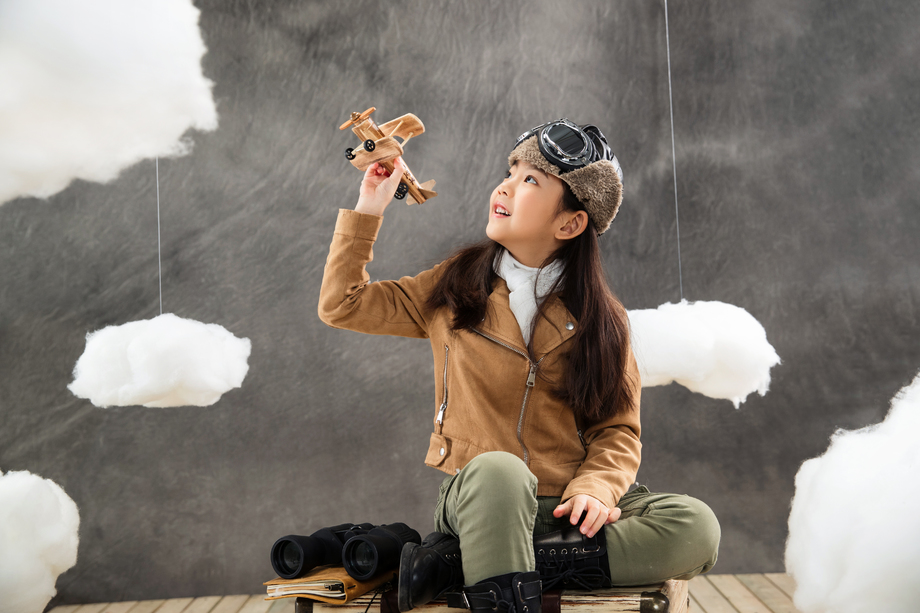 坐在行李箱上的女孩拿着飞机模型 坐在行李箱上的女孩拿着飞机模型