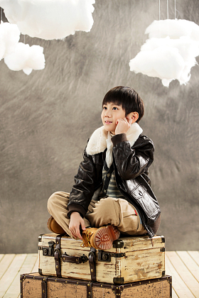 小男孩坐在行李箱上思考