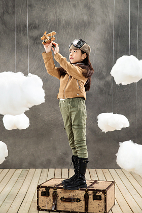 站在行李箱上的女孩拿着飞机模型